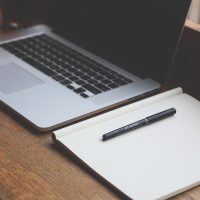 本机ip查询编辑部测试作者的实拍工作照：年轻工程师一手拿着两台手机、一手在笔记本上记录地址变化，桌上摊着不同系统的操作截图打印稿